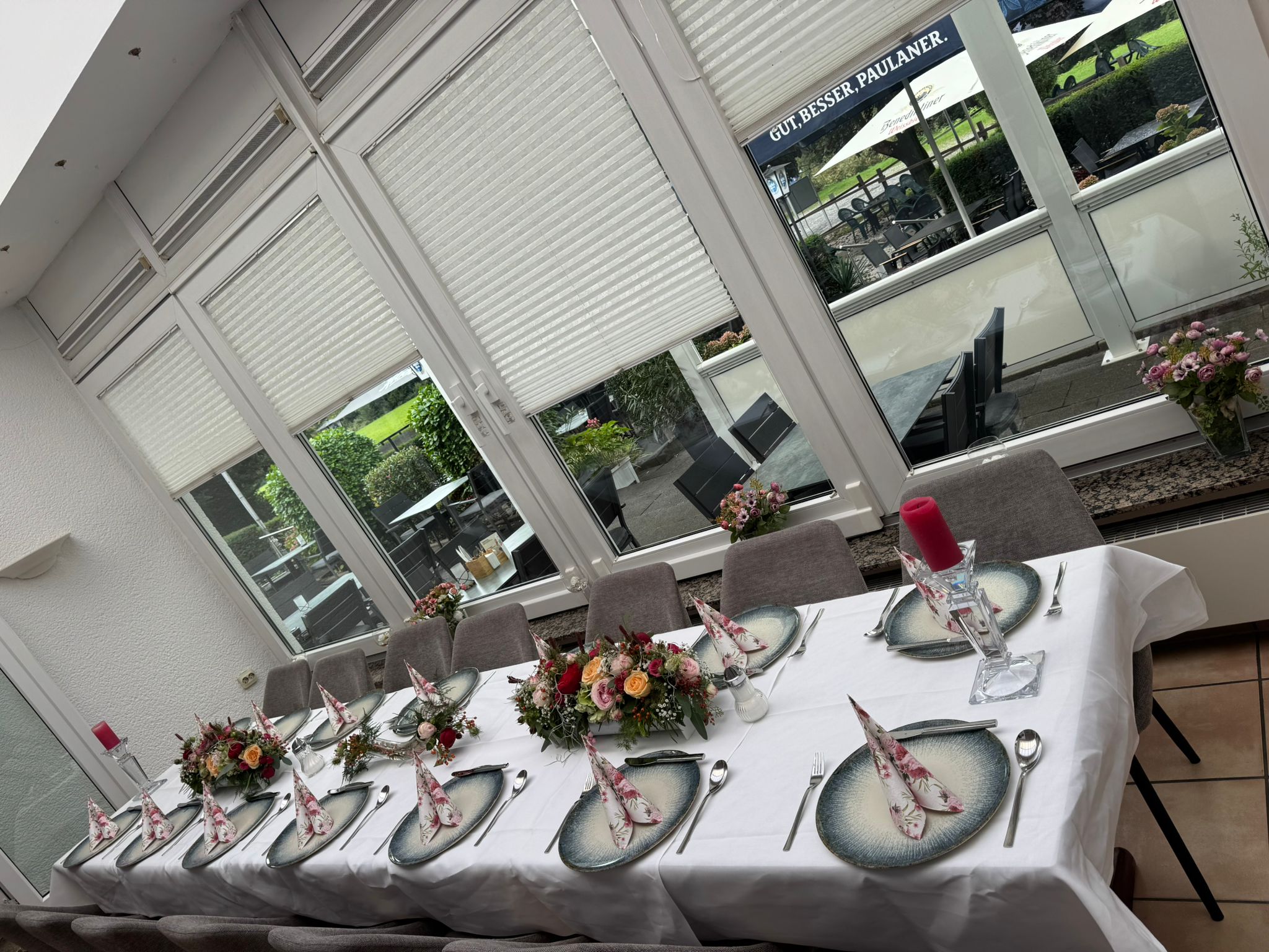 Eleganter Speisesaal mit formellen Tischdekorationen, bunten Tellern und Blumenarrangements